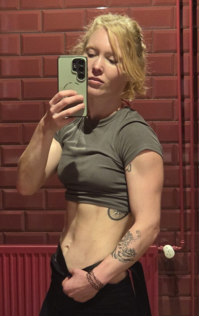 ERREICHE DEINE ZIELE IM OONLINE COACHING UND SEHE IM SPIEGEL AUS WIE EIN TIER DURCH TRAINIERTEN OBERKÖRPER BLONDE FRAU SPIEGELSELFIE